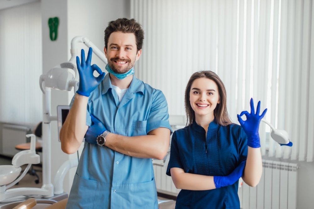 photo-smiling-dentist-standing-with-arms-crossed-with-her-colleague-showing-okay-sign.jpg